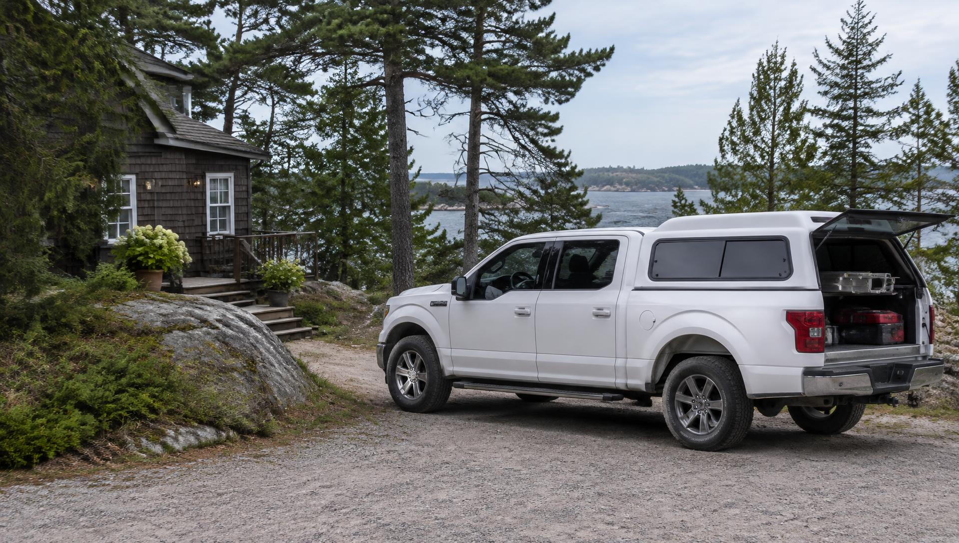 White four-door Ford F-150 with a white cap parked on a Georgian Bay cottage lane